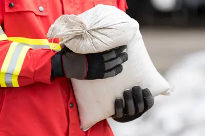 emergency worker carrying a sand bag