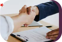 interviewer shaking hands with job applicant over a desk