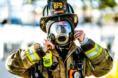 fireman dressed in full protective gear smiling and adjusting his helmet