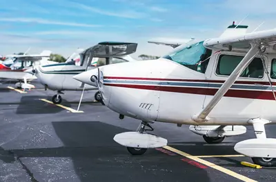 line of personal aircrafts parked on a runway.